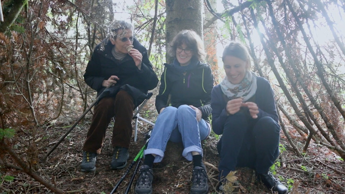 Trois femmes souriantes assises dans une forêt dans le documentaire « De la poussière dans les yeux »