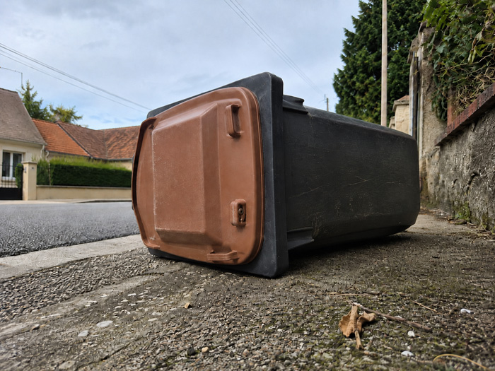 Poubelle brune renversée sur un trottoir, illustration de la réduction des déchets à Sausheim.